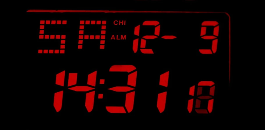 an electronic clock with red letters on a black surface