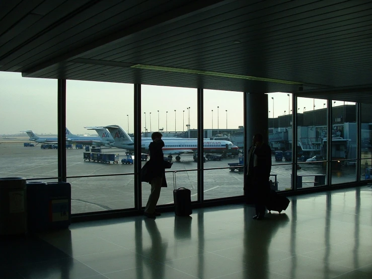 two people are waiting at an airport for the plane to pass