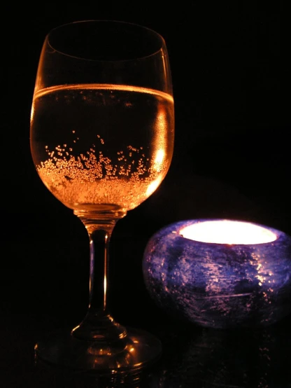 a lighted candle lit next to a glass with wine