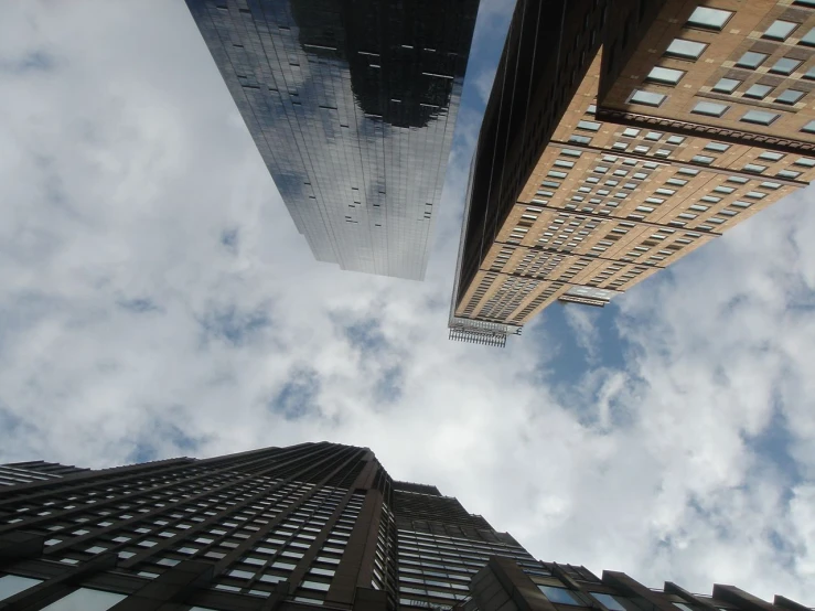 two skyscrs are seen from below in a cloudy sky