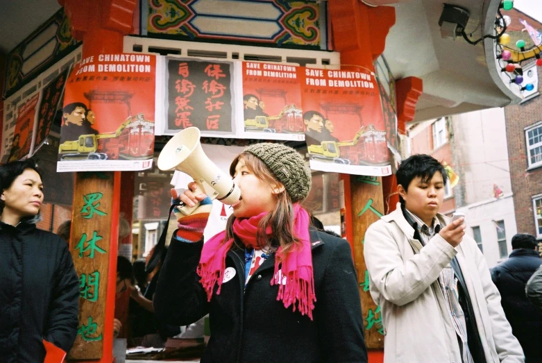 a woman holding a white bullhorn standing in front of a store