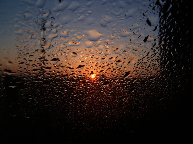 a sun shining through the rainy window in the rain