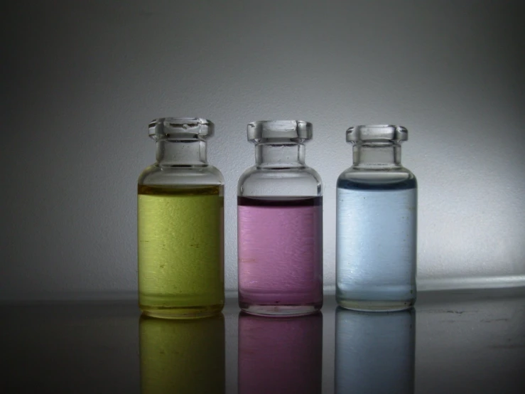 three bottles filled with different colored liquids sitting next to each other