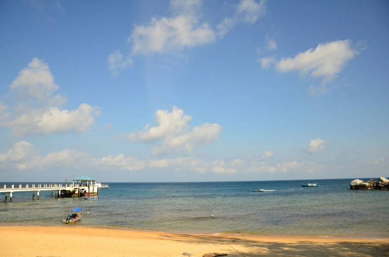 people on the beach in the ocean and boats floating in the water