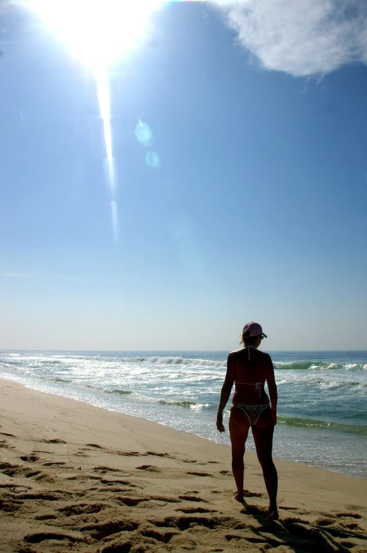 a woman standing on top of a beach under a sun