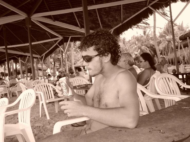 a man sitting under an umbrella drinking a glass of wine