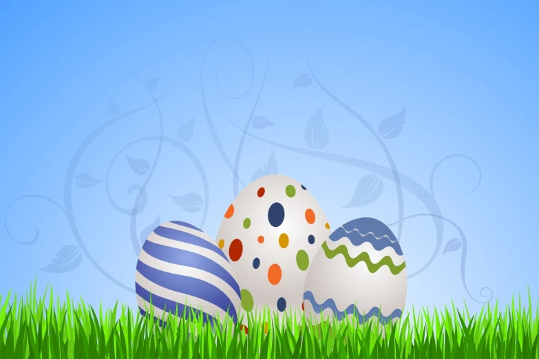 three decorated easter eggs in the grass