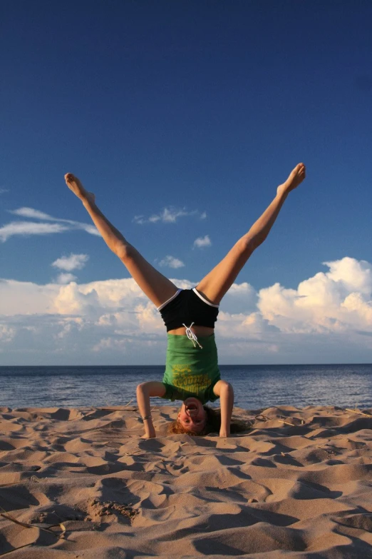 the woman is engaged in her gymnastics poses on the beach