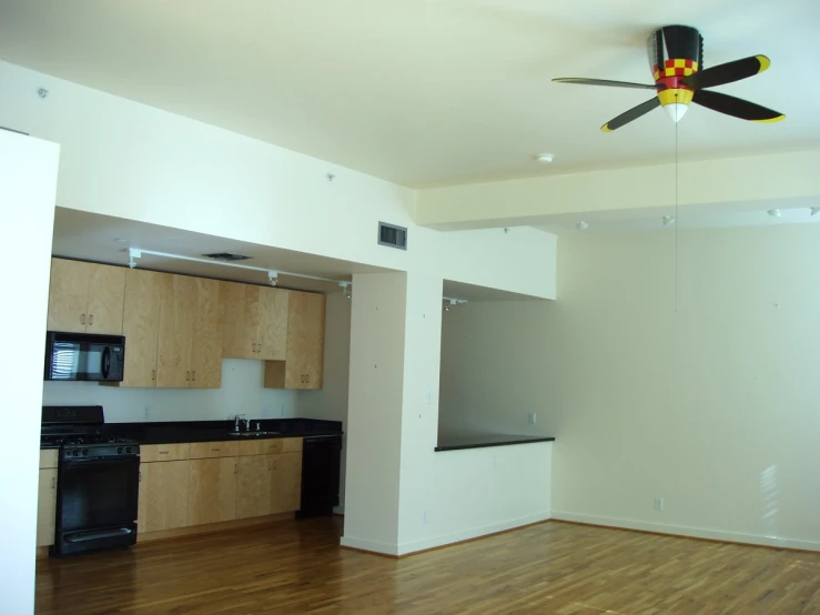 an empty kitchen that has a ceiling fan