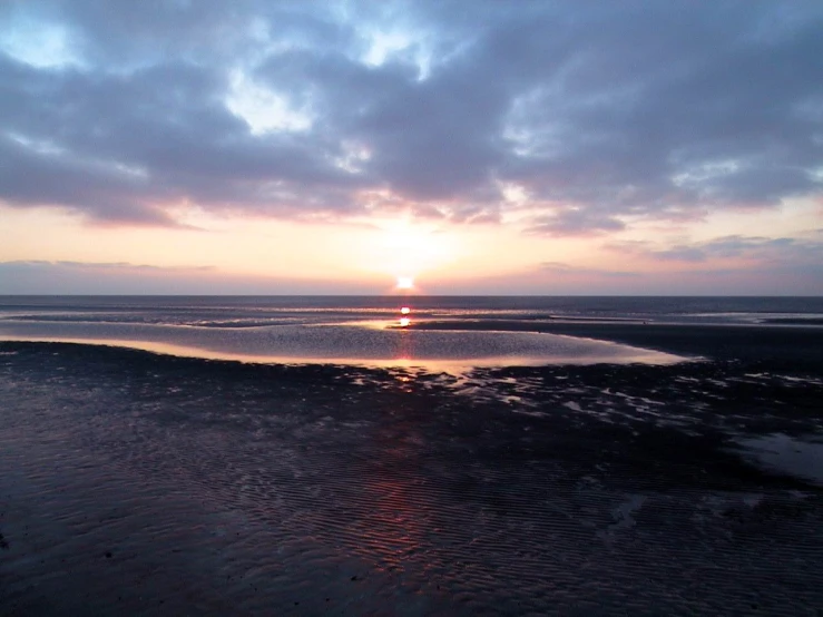 there is a beach with sunset on the water