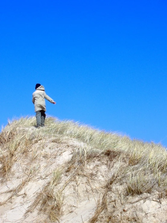 a man on a dune with his hands up