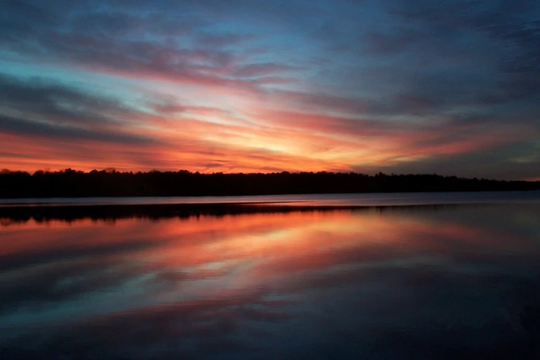 a calm evening over a lake with the sun going down