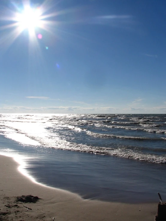 the sun shines brightly above a sandy beach with small waves