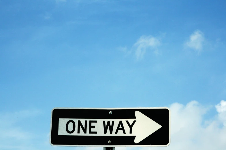 one way sign in front of the sky with clouds