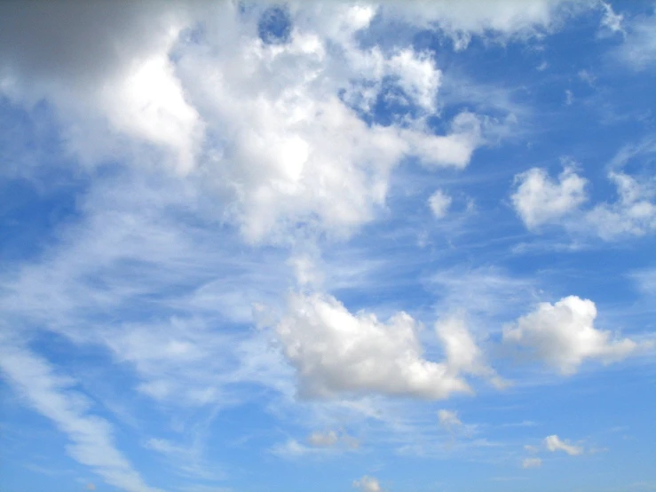 a large field of grass with blue sky and clouds