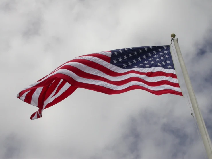 an american flag flying in the wind on a cloudy day