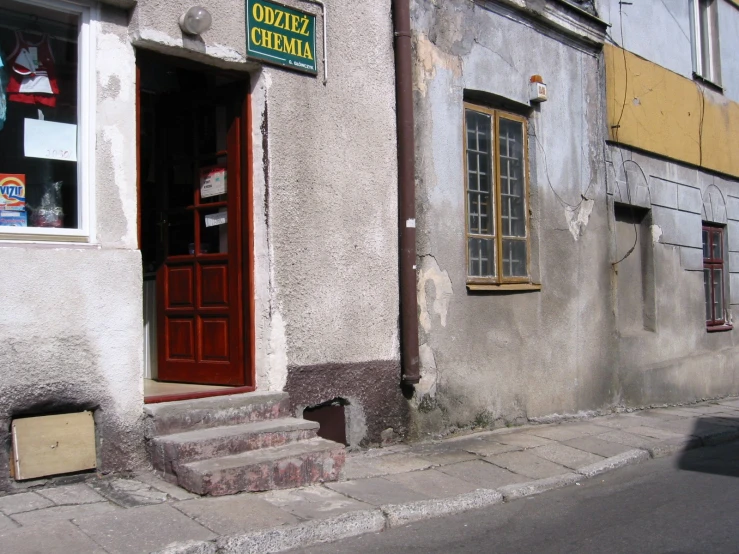 an old building with a red door, and a man walking down a sidewalk in front of it