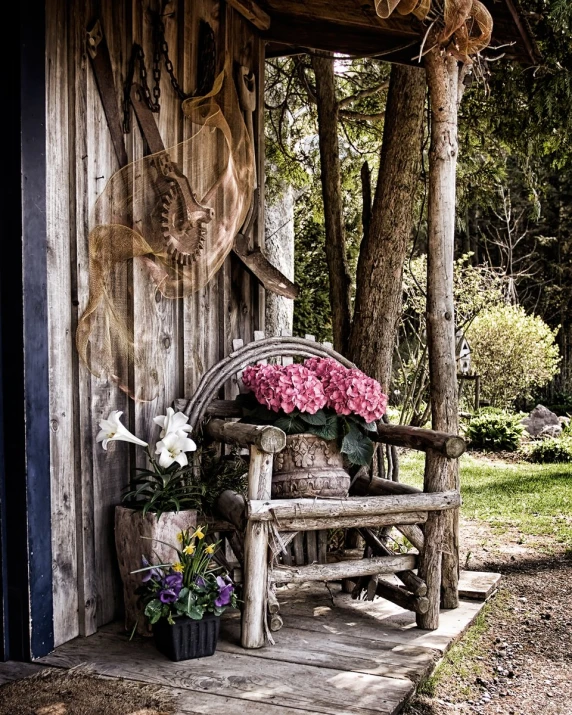 a wooden porch area with some plants in the pot and flowers in the back