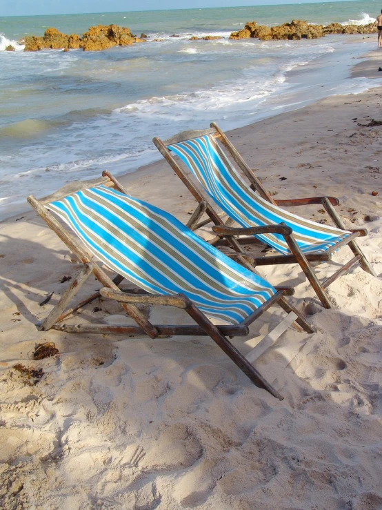 two beach chairs are set up on a sandy beach