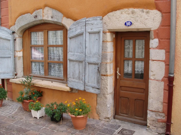 an old house with two open shutters and flower pots