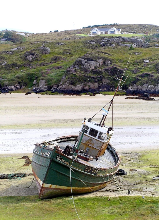 a green fishing boat sitting on the shore