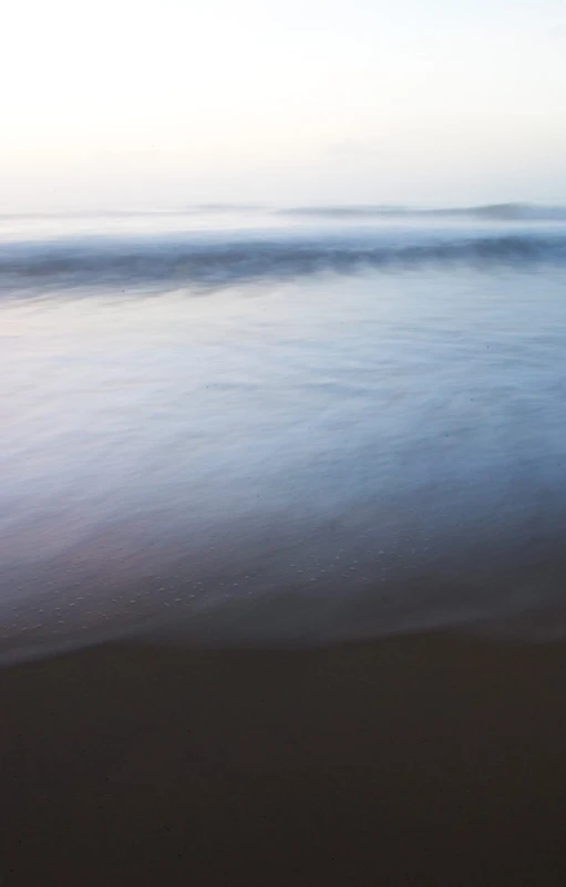 a large body of water with sand and a person on it