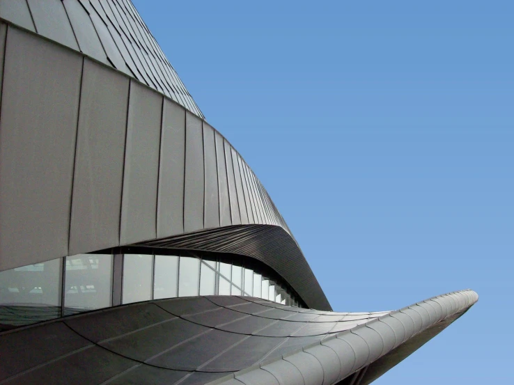 a blue sky looks over the curved side of a building