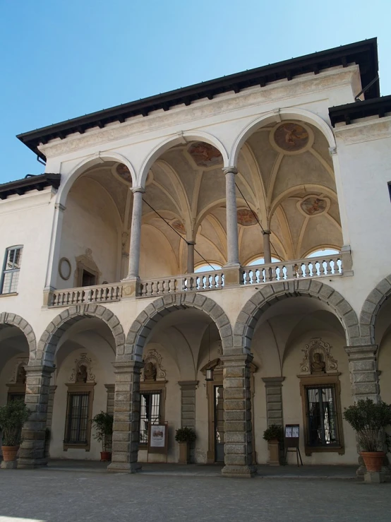 an elegant courtyard with stone arches, pots and potted plants