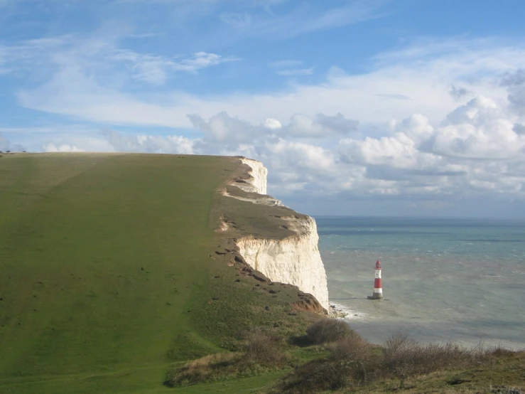 there is a white and red lighthouse next to the ocean