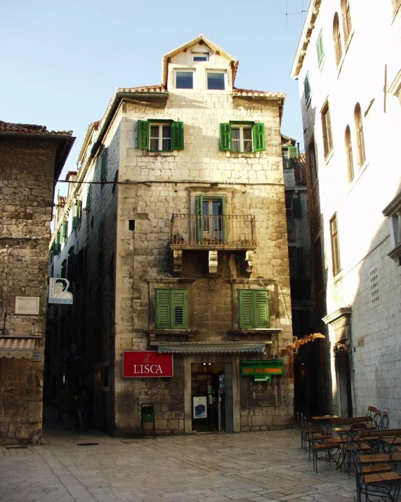 a stone building with lots of windows and wooden chairs