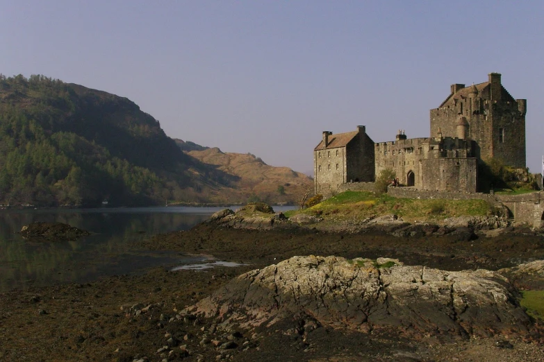 the castle is standing by the water with some mountains in the background