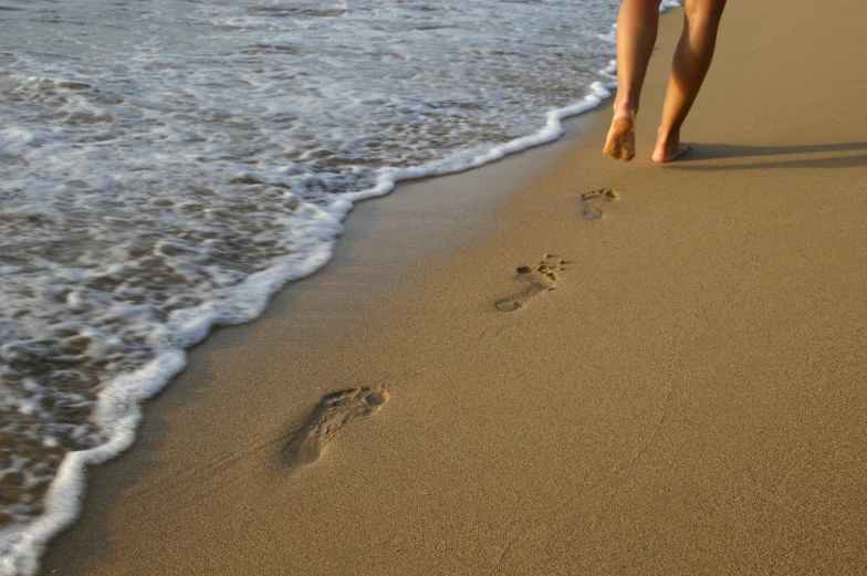 woman walking toward the ocean water holding her hand and foot