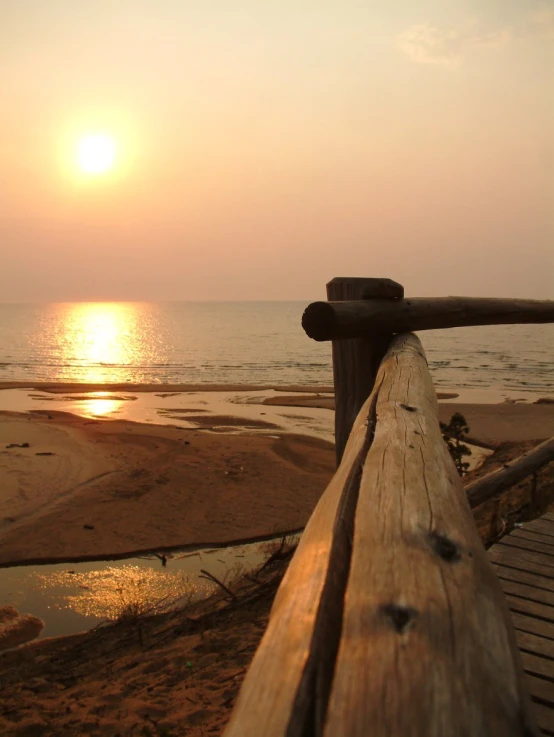 a wooden railing and sunset on an ocean beach