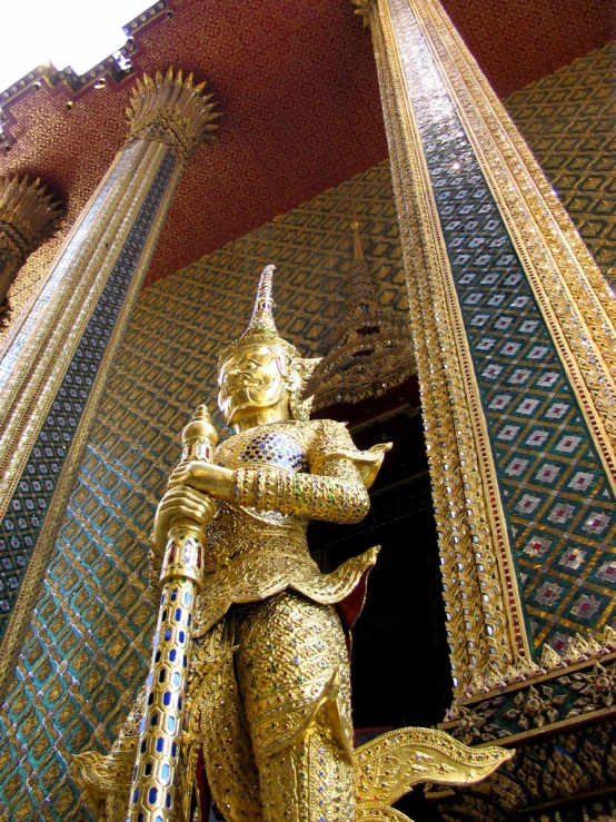 a statue in gold is standing next to two tall columns