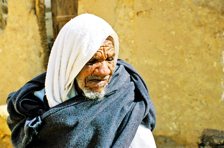 the elderly man is walking down the street carrying a large blanket