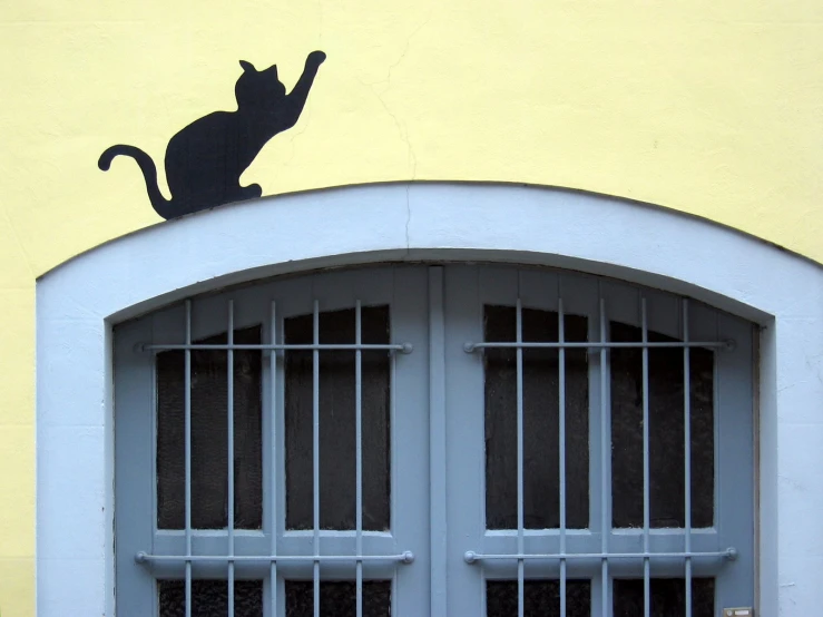 the cat has its head over the bars of the windows