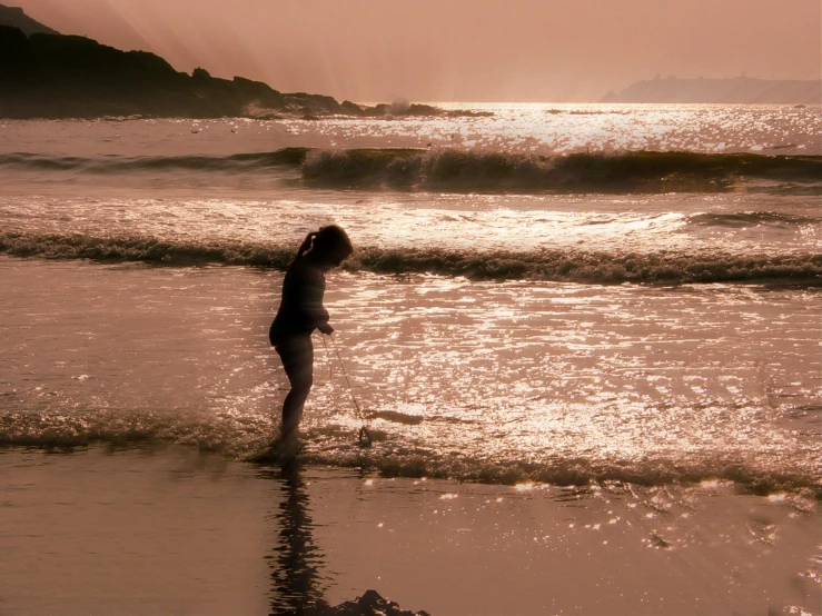 the girl is standing on the beach, holding her head in the water