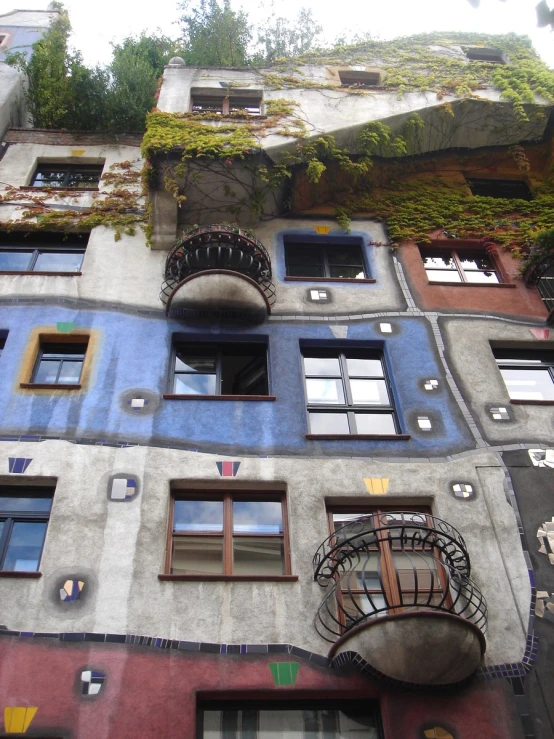 an old apartment building with balconies and lots of plants growing up the side