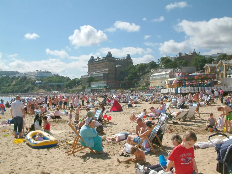 a crowded beach with lots of people, and lots of water in the background