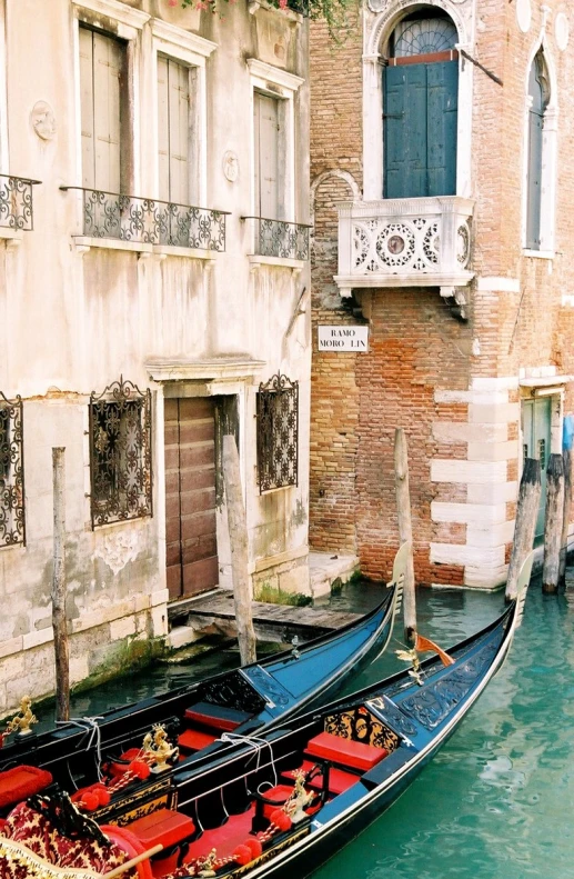 two gondolas on a canal near a building