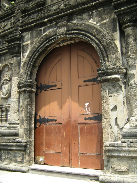 a brown door and two black handles in an old building