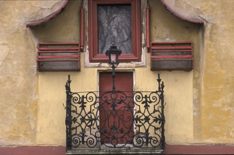 a red window mounted onto the side of a yellow building