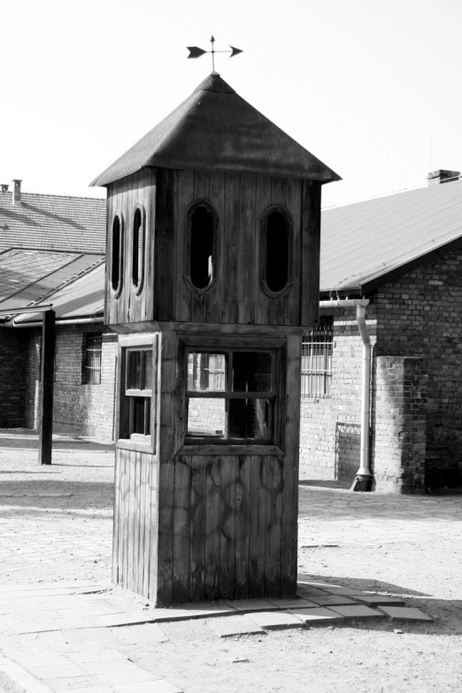 a tall wooden structure stands in the middle of a dirt field