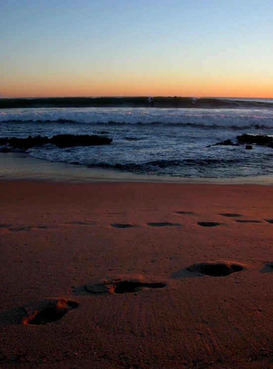 a person walking across a sandy beach next to the ocean