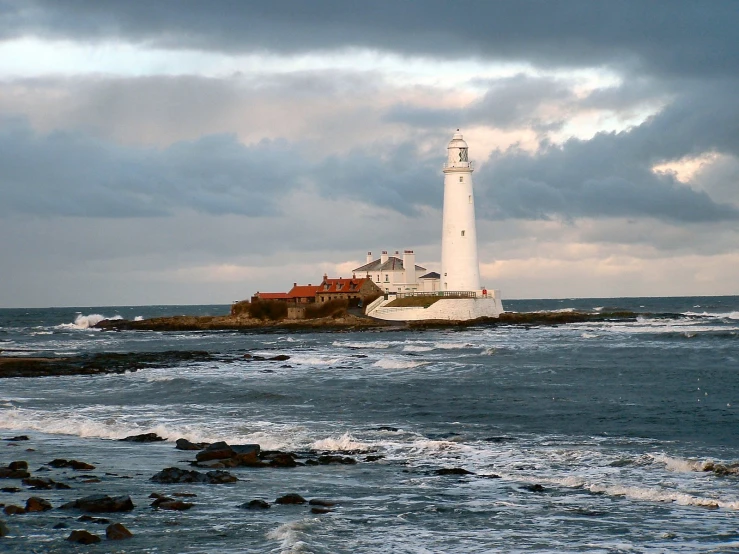 there is a white lighthouse with a red roof near the water