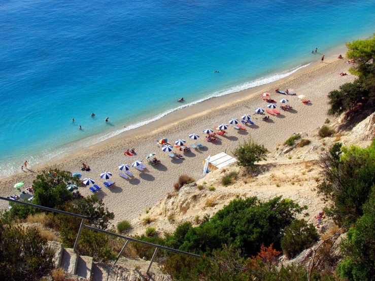 a beach that has some people and many umbrellas