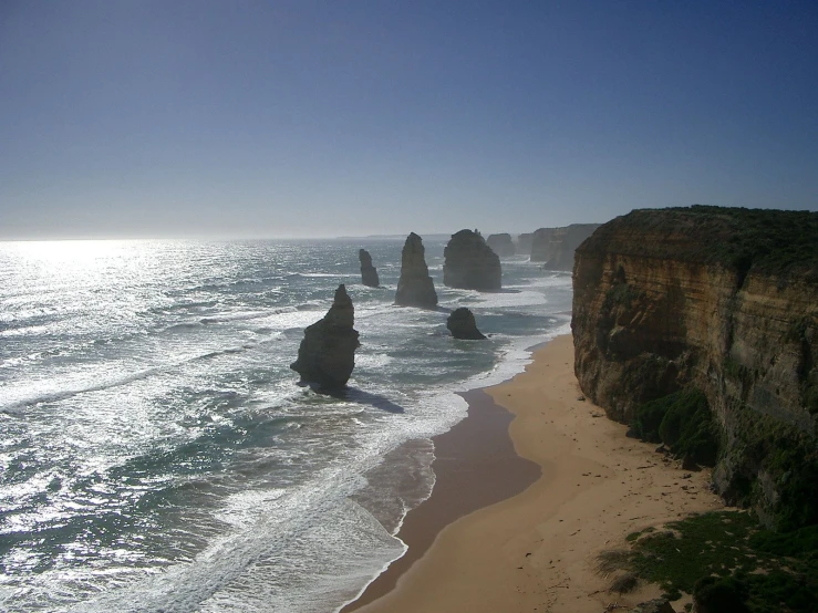 ocean water with sand and large rock formations near shore