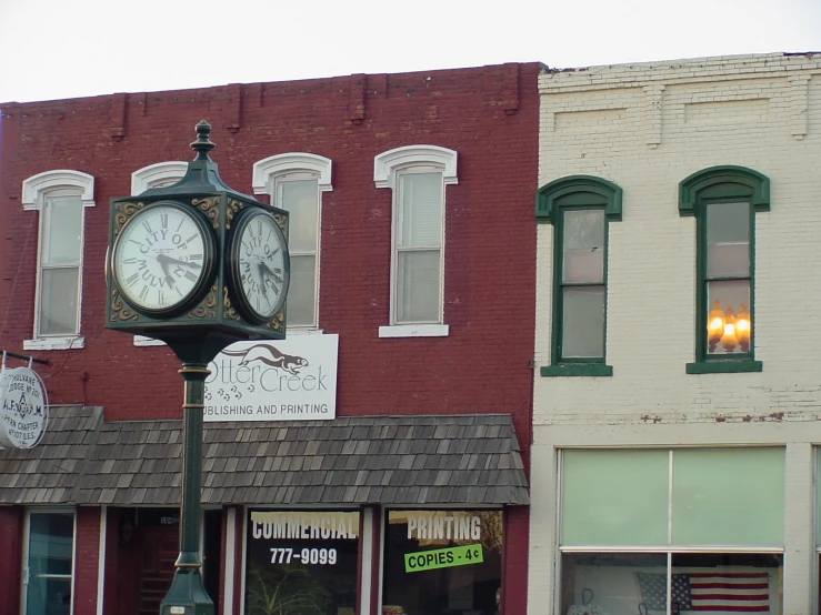 a pole with a clock sitting on the street in front of buildings