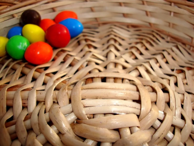 a basket with wood handles and lots of different colored balls