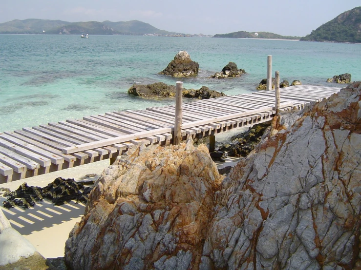 a pier next to the ocean is on a rocky beach